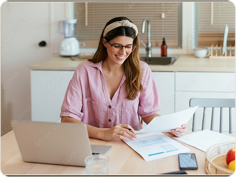 Woman at her desk working through paperwork with a laptop